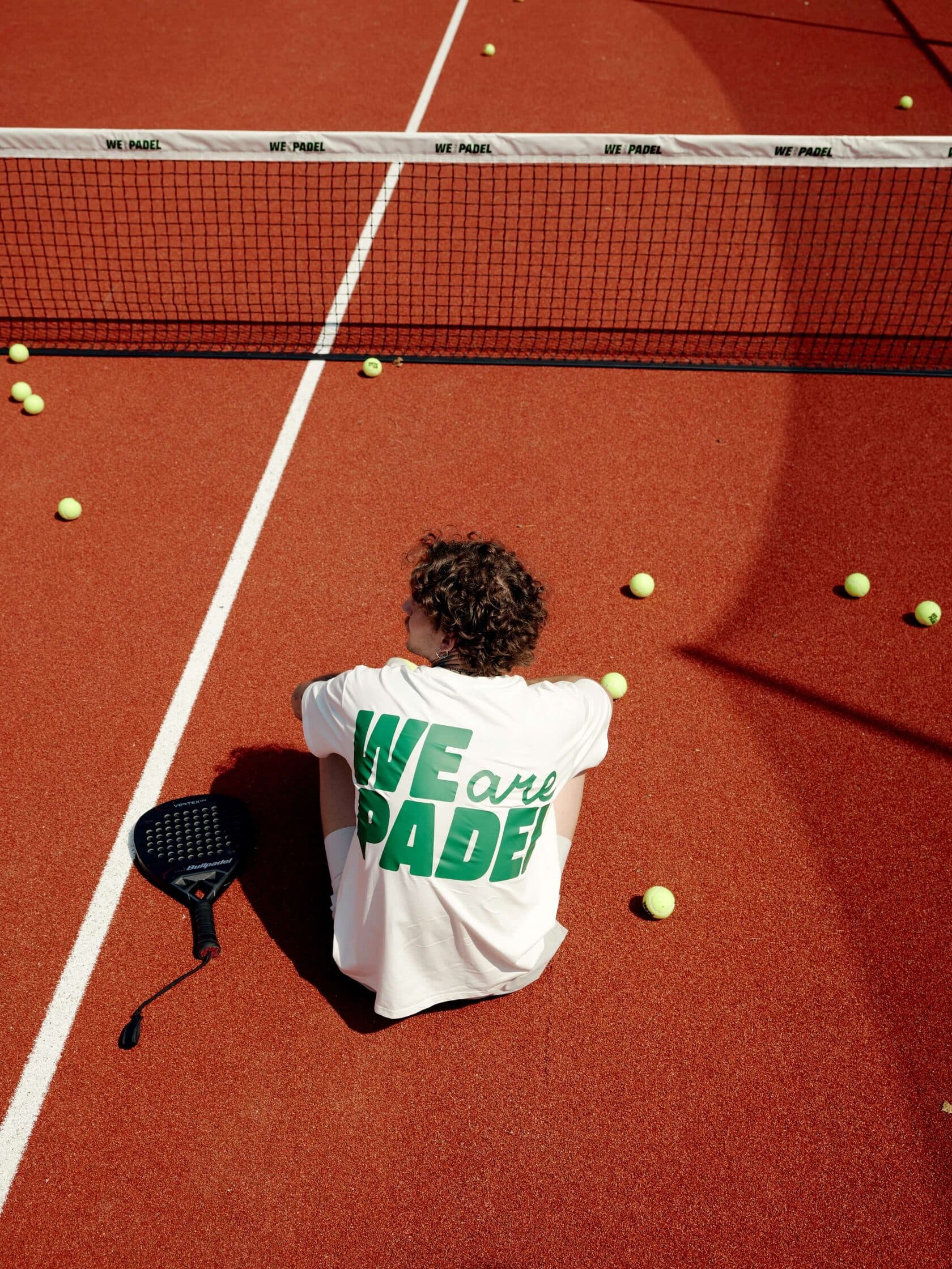 Гравець сидить на корті We are Padel